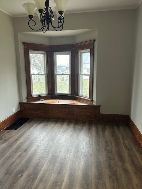 unfurnished room featuring a chandelier, baseboards, ornamental molding, and wood finished floors
