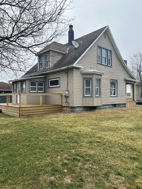 rear view of property with a yard, a deck, and a chimney