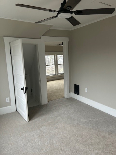 empty room featuring baseboards, crown molding, carpet floors, visible vents, and ceiling fan