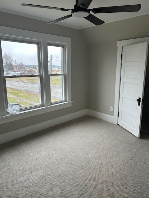 carpeted spare room with baseboards, a ceiling fan, and vaulted ceiling