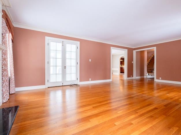 empty room featuring french doors, crown molding, and light hardwood / wood-style flooring