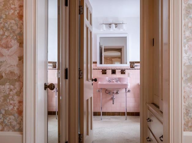 hallway featuring light colored carpet and tile walls