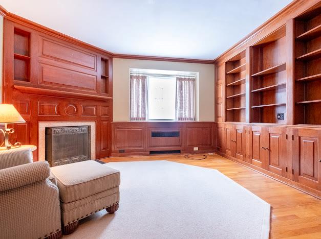 living room with built in shelves, radiator heating unit, light hardwood / wood-style floors, and ornamental molding