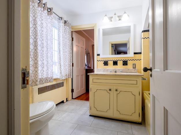 bathroom with tasteful backsplash, radiator, vanity, tile patterned flooring, and toilet