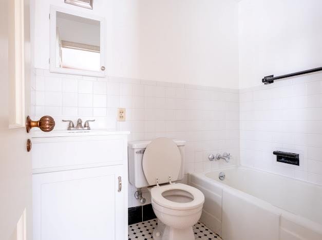 bathroom featuring a tub to relax in, vanity, tile walls, and toilet