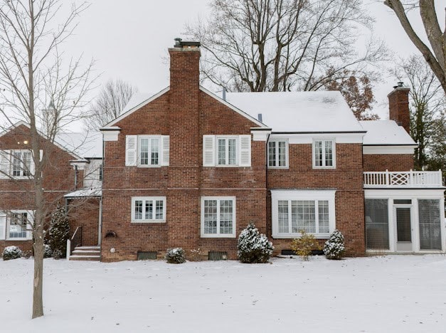 snow covered house featuring a balcony