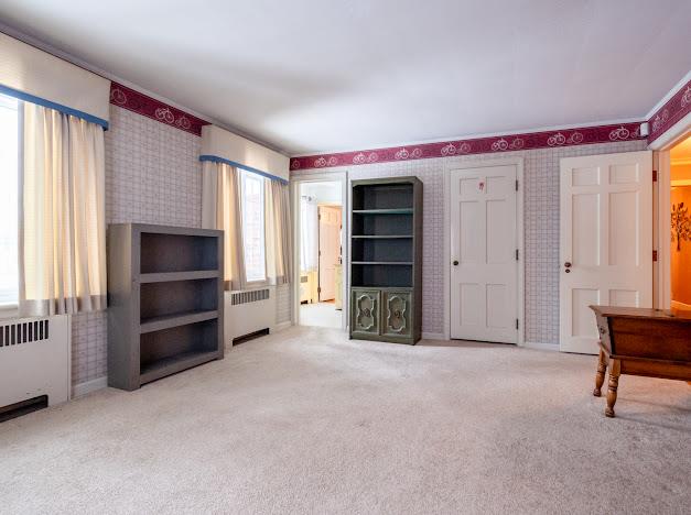 unfurnished living room featuring radiator heating unit and light carpet