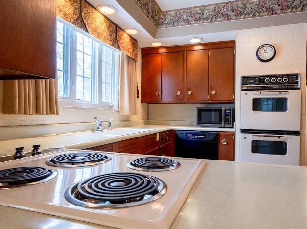 kitchen with sink, white double oven, stove, and black dishwasher