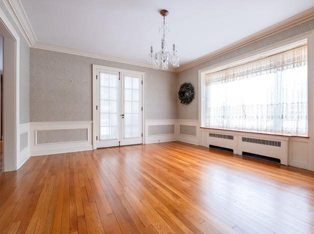 spare room with plenty of natural light, crown molding, radiator, and light hardwood / wood-style flooring