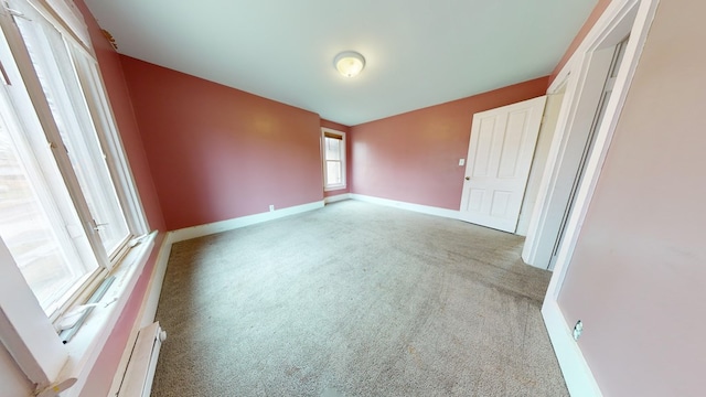 unfurnished bedroom featuring light carpet and baseboard heating