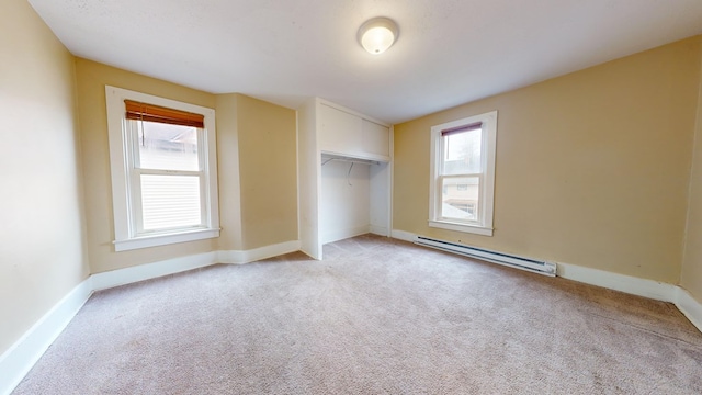 unfurnished bedroom with multiple windows, light colored carpet, and baseboard heating