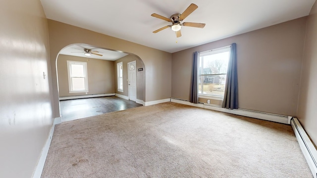 carpeted spare room with ceiling fan, a baseboard radiator, and plenty of natural light