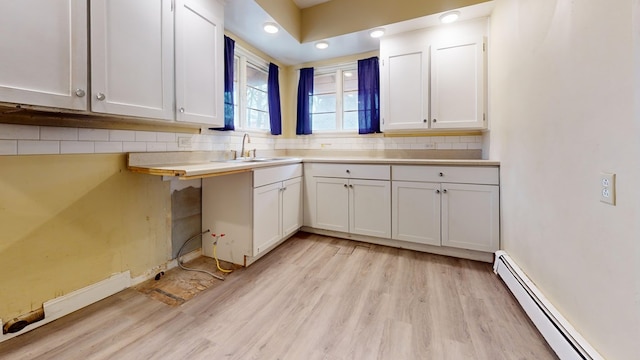 kitchen featuring sink, white cabinets, and baseboard heating