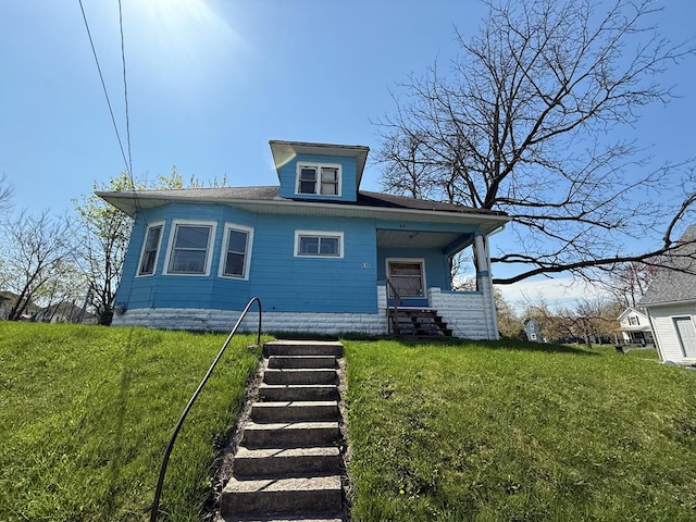 bungalow featuring a porch, a front lawn, and stairway