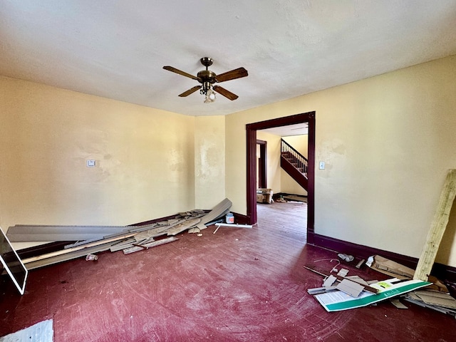 spare room featuring stairway, baseboards, and a ceiling fan