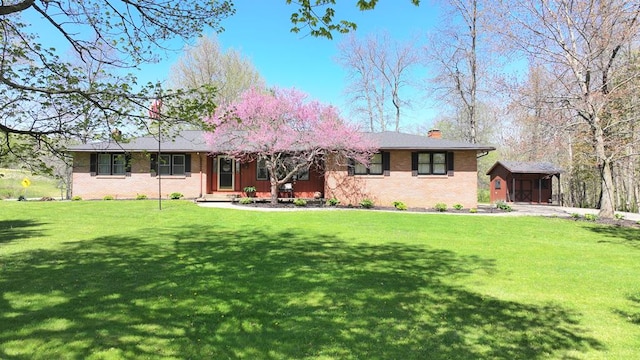 ranch-style home featuring brick siding, a front lawn, and a chimney