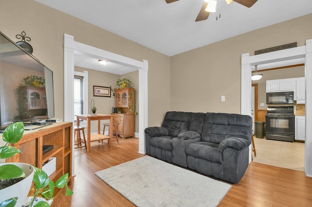 living room featuring a ceiling fan and light wood-type flooring