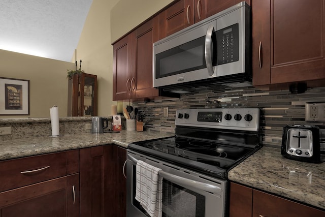 810 Whippoorwill Ln, Mansfield, OH 44906 - kitchen featuring appliances with stainless steel finishes, backsplash, light stone counters, lofted ceiling, and a peninsula