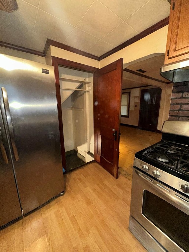 kitchen with brown cabinets, appliances with stainless steel finishes, light wood-style flooring, and crown molding