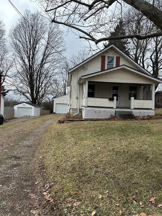 bungalow-style home featuring a porch, an outbuilding, a front yard, and a detached garage