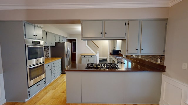 kitchen with kitchen peninsula, stainless steel appliances, crown molding, and sink