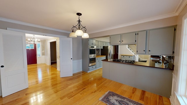 kitchen featuring kitchen peninsula, stainless steel appliances, light hardwood / wood-style flooring, a chandelier, and hanging light fixtures