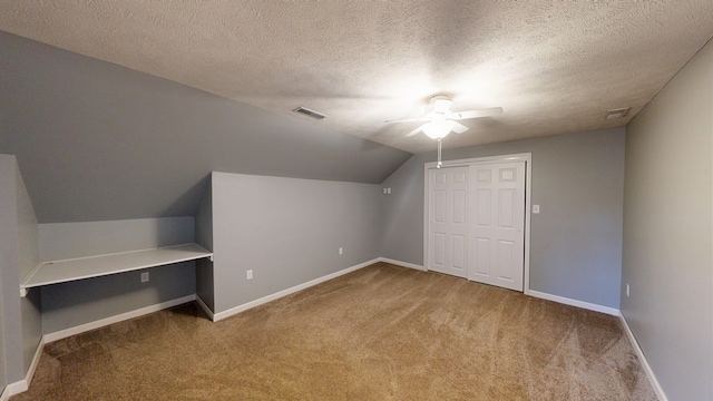 additional living space with a textured ceiling, carpet floors, vaulted ceiling, and ceiling fan