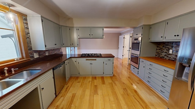 kitchen featuring backsplash, stainless steel appliances, gray cabinetry, and light hardwood / wood-style floors