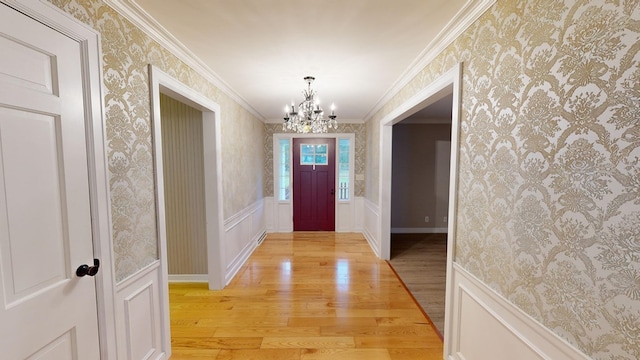 entrance foyer featuring light hardwood / wood-style floors, an inviting chandelier, and ornamental molding