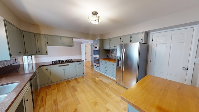 kitchen with decorative backsplash, appliances with stainless steel finishes, gray cabinets, and light hardwood / wood-style floors