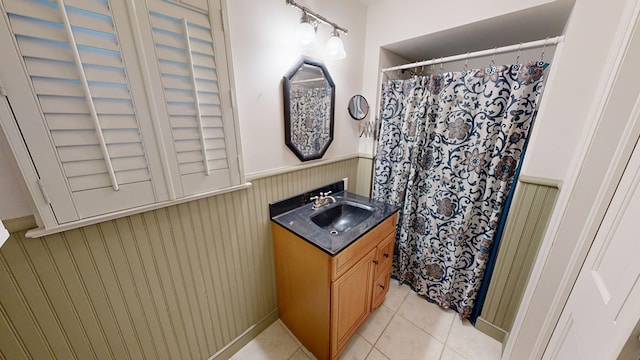 bathroom with tile patterned floors, wood walls, vanity, and walk in shower