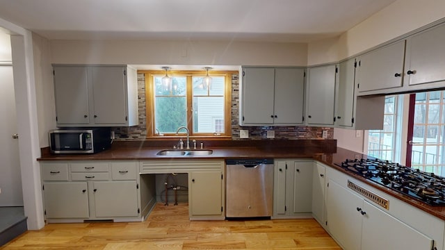 kitchen featuring decorative backsplash, sink, light wood-type flooring, and appliances with stainless steel finishes