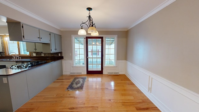 doorway to outside with light hardwood / wood-style flooring, ornamental molding, sink, and an inviting chandelier