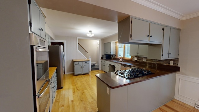 kitchen with sink, gray cabinets, light wood-type flooring, ornamental molding, and appliances with stainless steel finishes