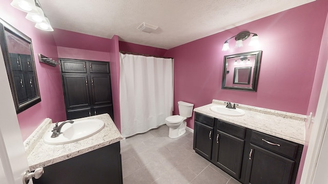 bathroom with tile patterned floors, vanity, toilet, and a textured ceiling