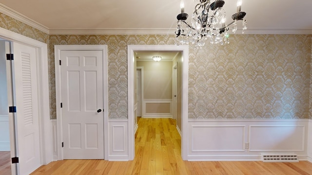 unfurnished dining area with crown molding, a chandelier, and light wood-type flooring