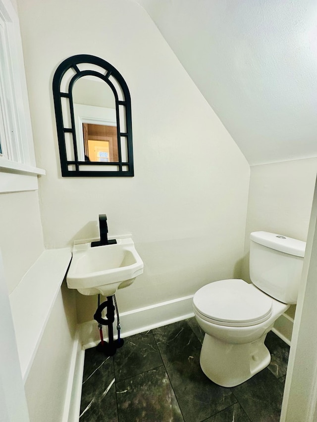 bathroom with sink, vaulted ceiling, and toilet