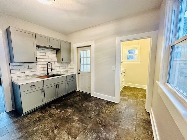 kitchen with backsplash, gray cabinets, plenty of natural light, and sink