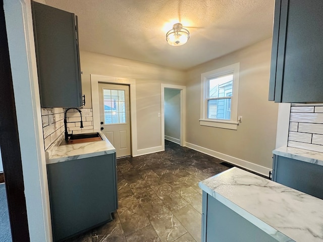 kitchen with a textured ceiling, decorative backsplash, sink, and plenty of natural light