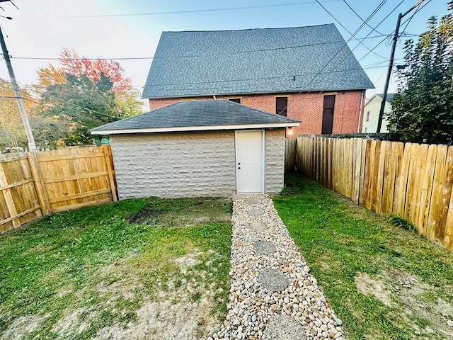 back of house featuring a yard and an outdoor structure