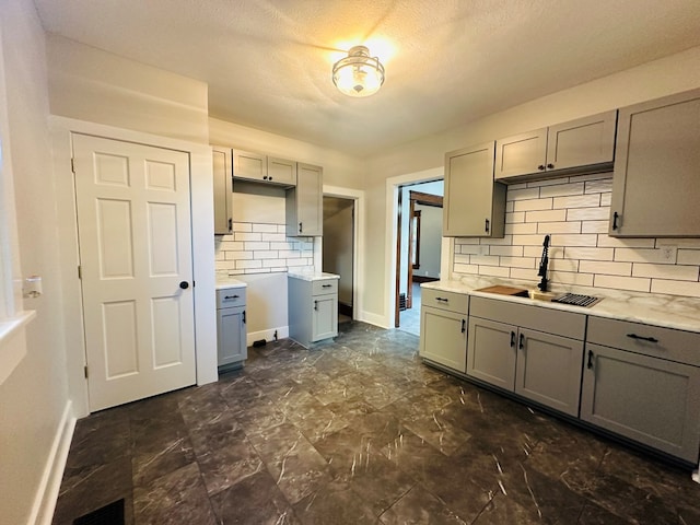 kitchen featuring backsplash, gray cabinetry, and sink