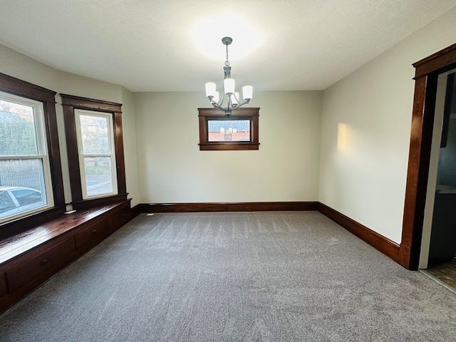 empty room with a textured ceiling, carpet floors, and an inviting chandelier