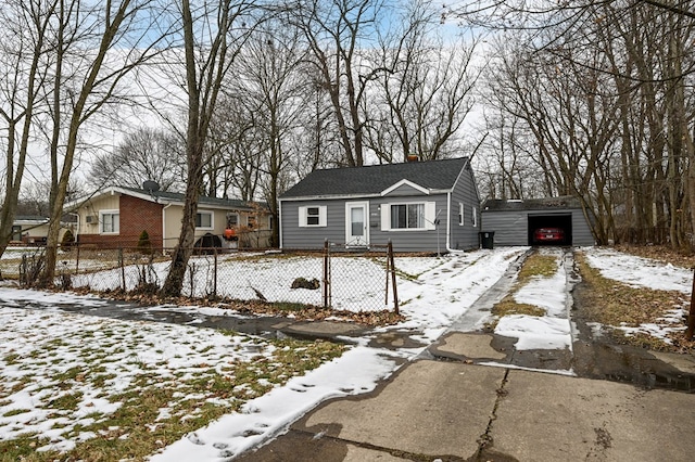 bungalow-style home featuring a chimney, a fenced front yard, a detached garage, and an outdoor structure