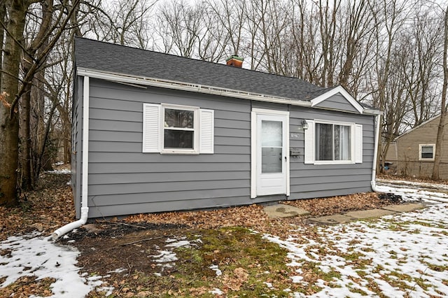 exterior space with roof with shingles and a chimney