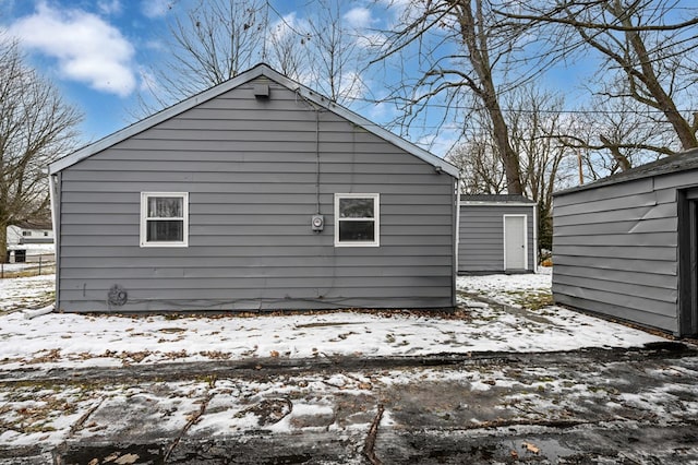 view of snow covered exterior featuring a storage shed and an outdoor structure