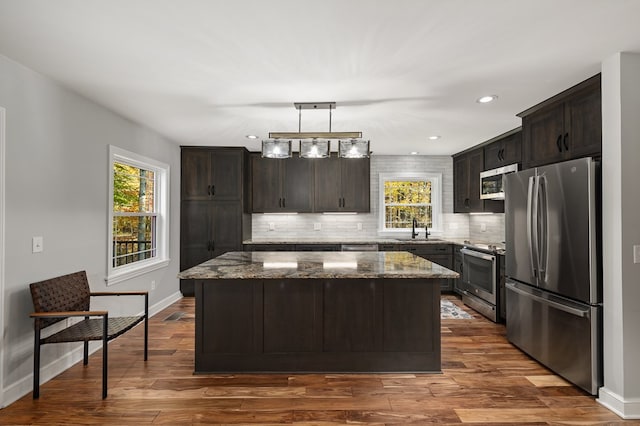 kitchen featuring hanging light fixtures, a kitchen island, sink, and appliances with stainless steel finishes