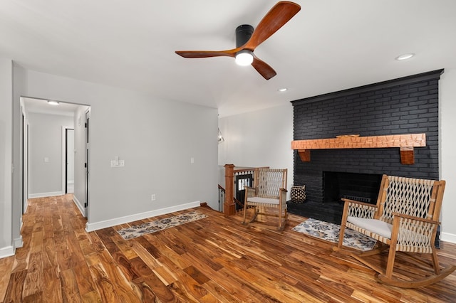 unfurnished living room featuring ceiling fan, a fireplace, and wood-type flooring