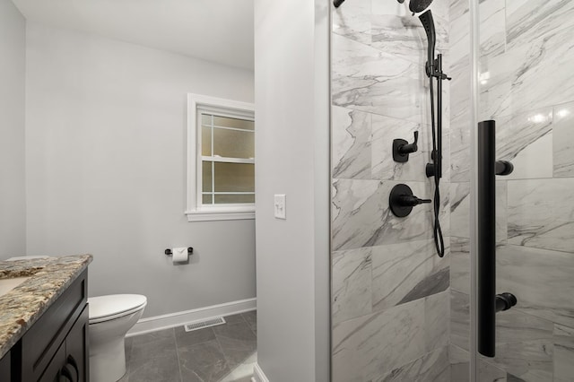 bathroom with a tile shower, vanity, and toilet