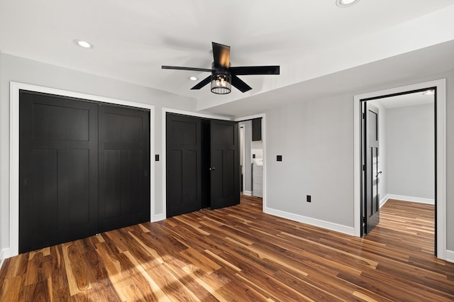 unfurnished bedroom with ceiling fan and dark wood-type flooring