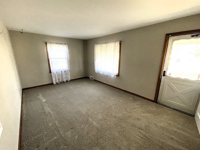 carpeted empty room featuring visible vents and baseboards